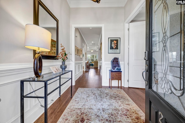 entrance foyer featuring a wainscoted wall, ornamental molding, dark wood finished floors, and a decorative wall