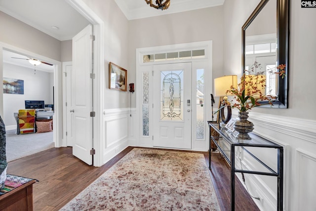 entryway with plenty of natural light, dark wood finished floors, wainscoting, and ornamental molding