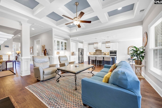 living room featuring wood finished floors, a ceiling fan, visible vents, decorative columns, and ornamental molding