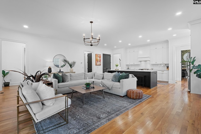 living room with recessed lighting, light wood-type flooring, and an inviting chandelier