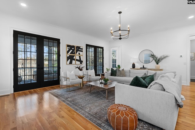 living area featuring a wealth of natural light, a notable chandelier, french doors, and wood finished floors