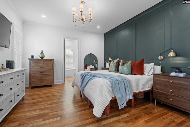 bedroom with recessed lighting, light wood-type flooring, a notable chandelier, and a decorative wall