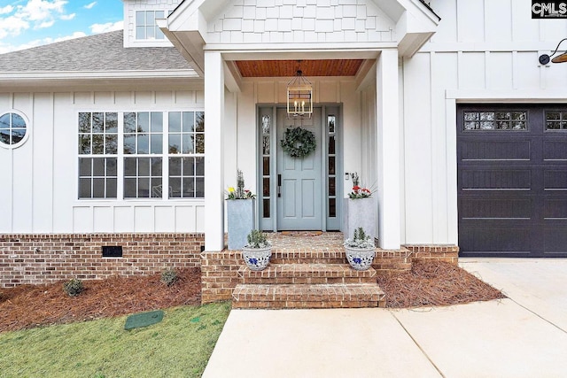 view of exterior entry with driveway, a shingled roof, a garage, crawl space, and board and batten siding