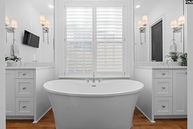 bathroom with a freestanding tub, wood finished floors, and vanity