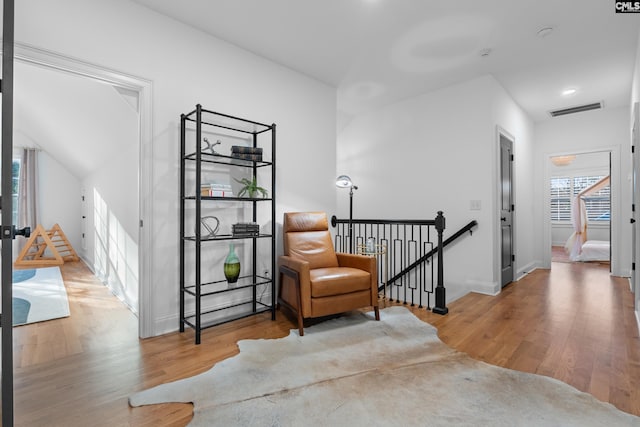 living area featuring visible vents, an upstairs landing, baseboards, and wood finished floors