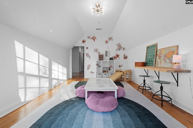 playroom with visible vents, a notable chandelier, wood finished floors, baseboards, and vaulted ceiling