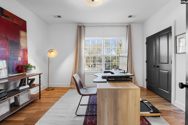 office area with visible vents, baseboards, and wood finished floors