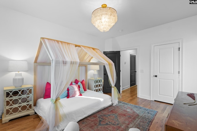 bedroom featuring baseboards, a notable chandelier, and wood finished floors