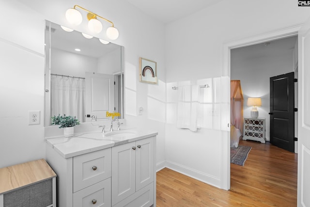 ensuite bathroom featuring vanity, wood finished floors, baseboards, and connected bathroom