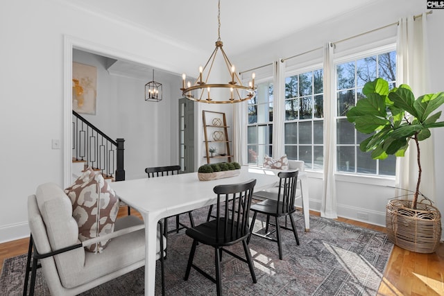 dining area with a chandelier, stairs, baseboards, and wood finished floors