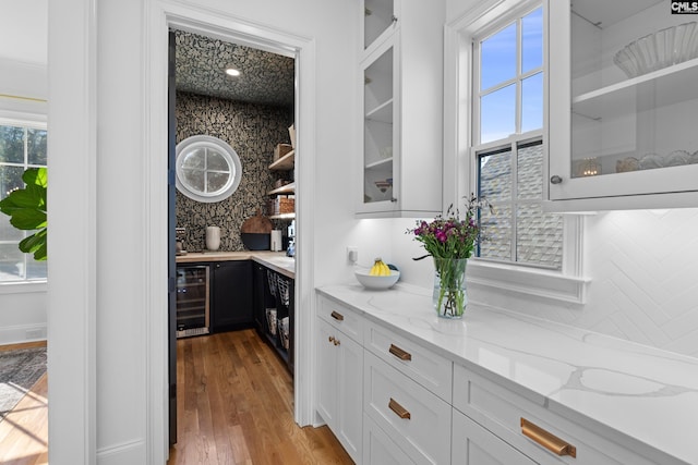 bar with beverage cooler, backsplash, and wood finished floors