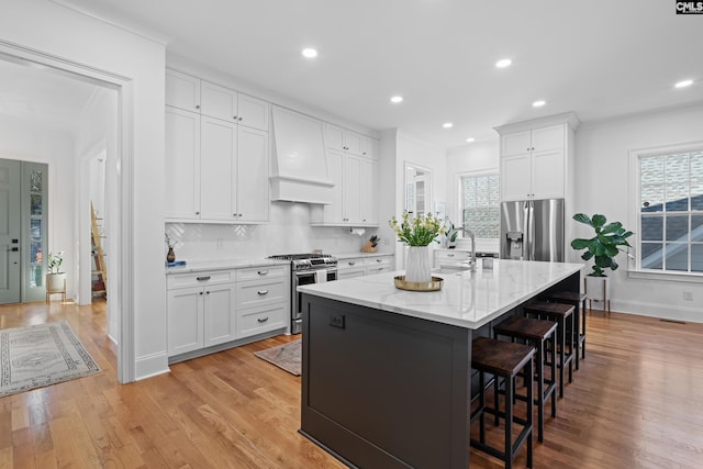 kitchen with a breakfast bar, light wood-style flooring, custom range hood, tasteful backsplash, and appliances with stainless steel finishes