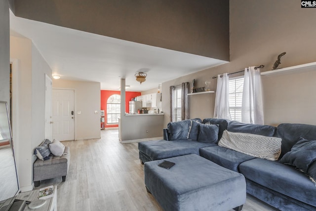 living area with light wood-type flooring, baseboards, and a healthy amount of sunlight