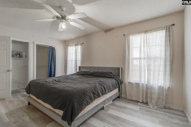 bedroom with light wood finished floors, baseboards, a textured ceiling, and ceiling fan