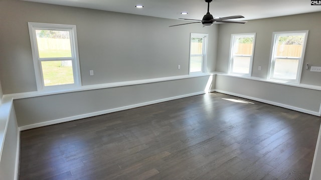 empty room featuring dark wood finished floors, a ceiling fan, and baseboards