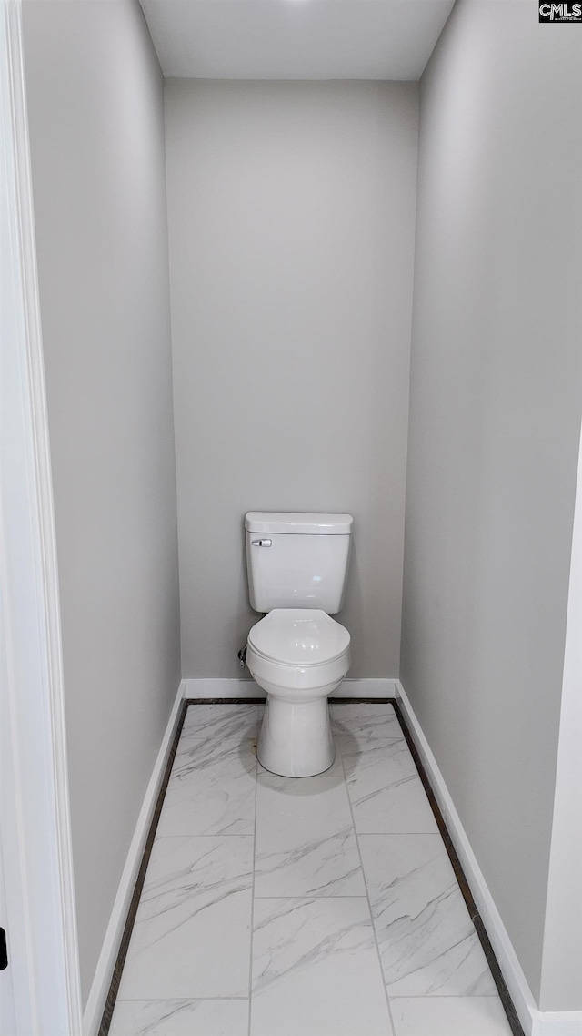 bathroom with baseboards, toilet, and marble finish floor