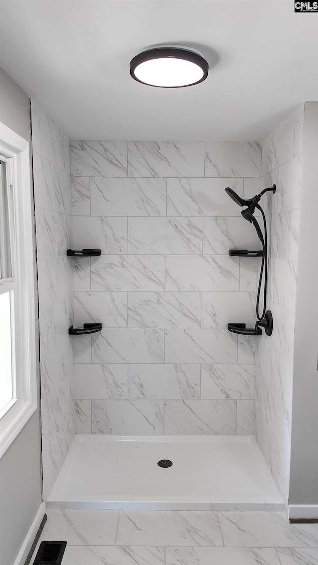 full bathroom with a tile shower, visible vents, and marble finish floor