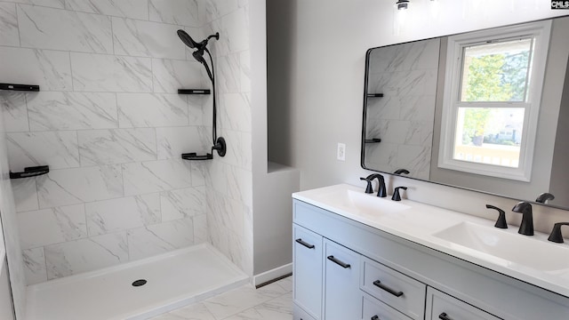 full bathroom featuring double vanity, marble finish floor, a tile shower, and a sink