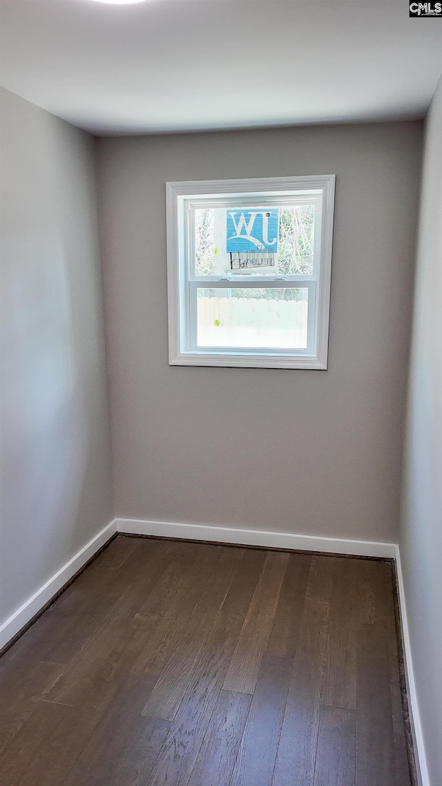 spare room featuring dark wood-type flooring and baseboards