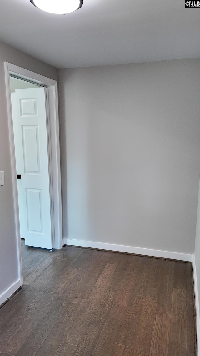 unfurnished room featuring baseboards and dark wood-style flooring