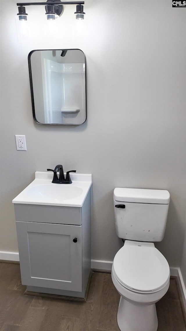 bathroom with vanity, toilet, wood finished floors, and baseboards