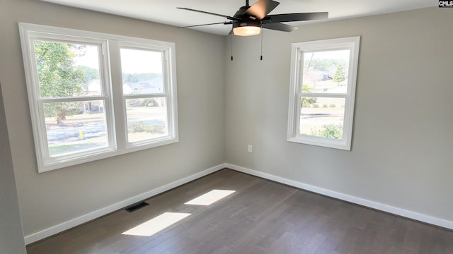 spare room with visible vents, baseboards, dark wood-type flooring, and a ceiling fan