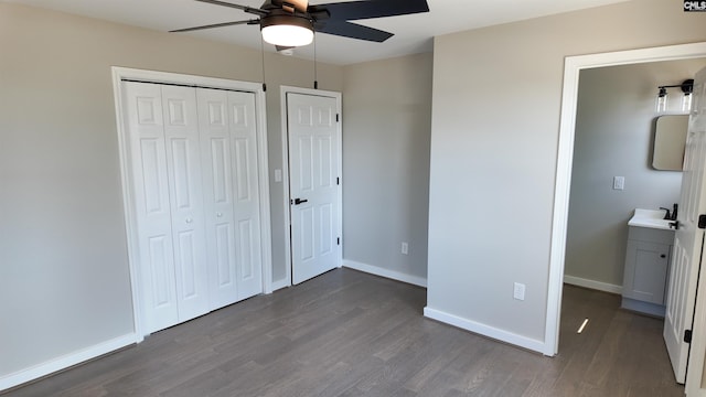 unfurnished bedroom with a ceiling fan, baseboards, dark wood finished floors, a sink, and a closet