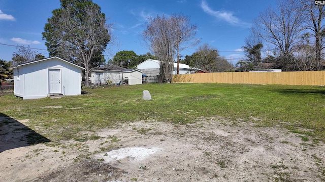 view of yard with an outbuilding, a storage shed, and fence