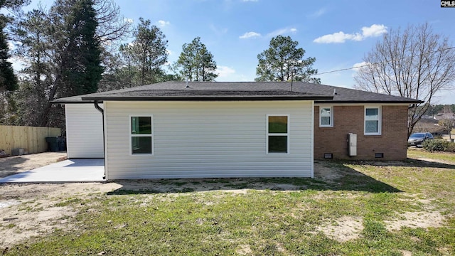 rear view of house with brick siding, fence, a lawn, crawl space, and a patio