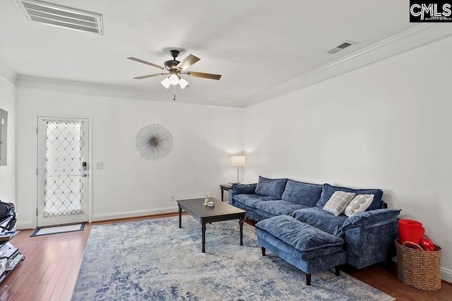 living area with visible vents, baseboards, ceiling fan, ornamental molding, and wood finished floors