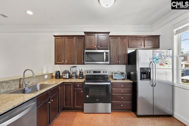 kitchen with light wood finished floors, visible vents, crown molding, stainless steel appliances, and a sink