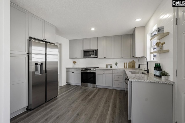 kitchen with a sink, dark wood finished floors, gray cabinets, stainless steel appliances, and open shelves