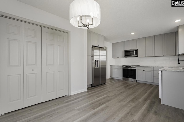 kitchen featuring a sink, light wood-style flooring, gray cabinetry, and stainless steel appliances