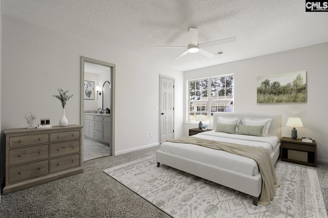 bedroom with a textured ceiling, light colored carpet, visible vents, and connected bathroom