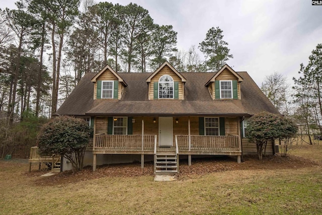 view of front of home with a front lawn, covered porch, and a shingled roof