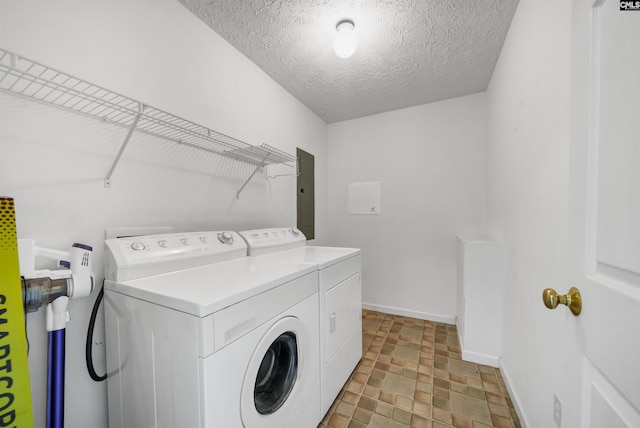 clothes washing area featuring baseboards, washer and clothes dryer, electric panel, laundry area, and a textured ceiling