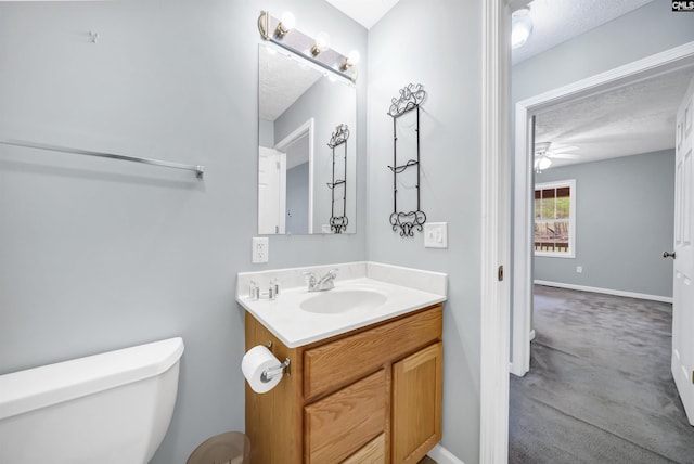 half bathroom with baseboards, ceiling fan, toilet, vanity, and a textured ceiling