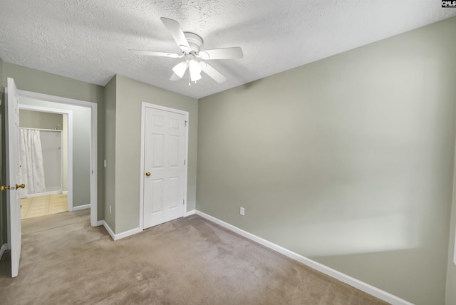 unfurnished bedroom with carpet flooring, a ceiling fan, baseboards, and a textured ceiling