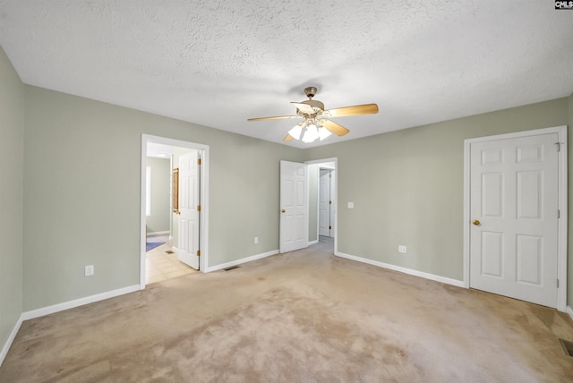 unfurnished bedroom featuring visible vents, baseboards, a textured ceiling, light colored carpet, and connected bathroom