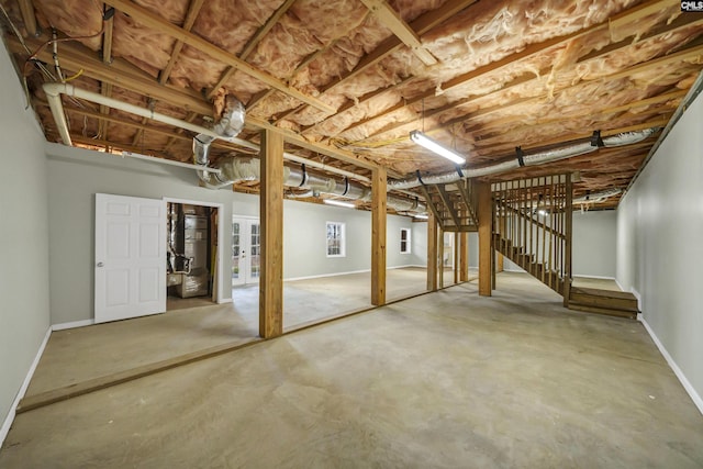 unfinished basement featuring stairway and baseboards