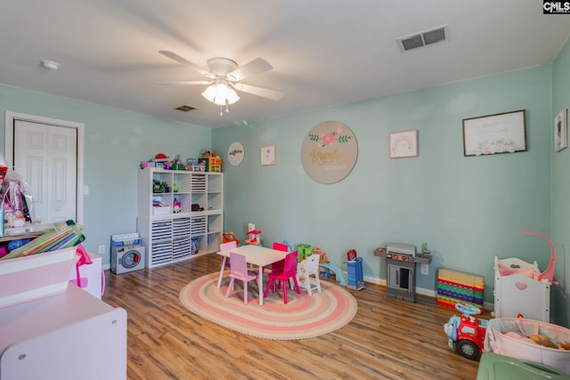 rec room with baseboards, wood finished floors, visible vents, and ceiling fan