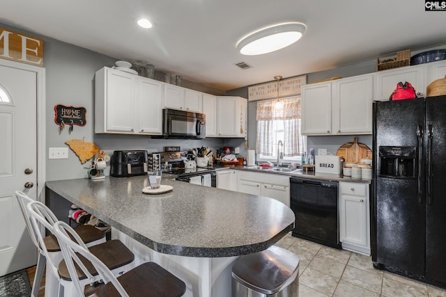 kitchen with black appliances, dark countertops, visible vents, and a sink