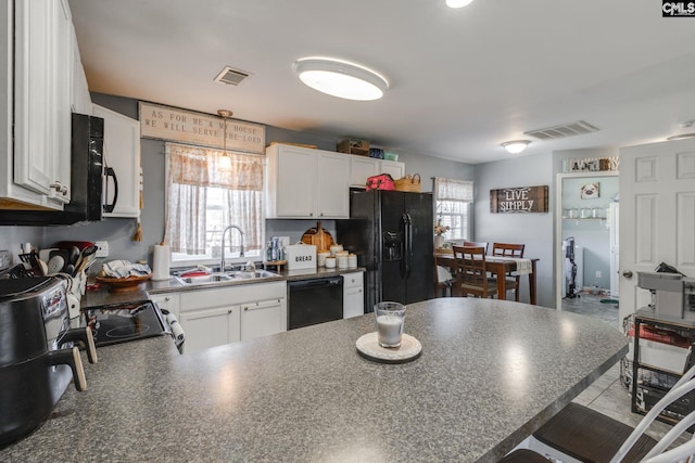 kitchen with black appliances, dark countertops, visible vents, and a sink