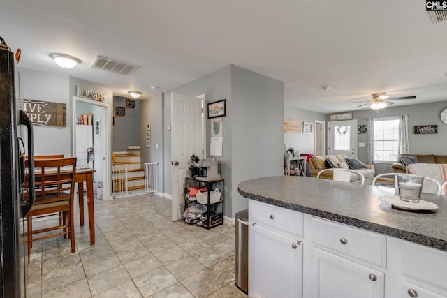 kitchen with visible vents, a ceiling fan, dark countertops, freestanding refrigerator, and white cabinets