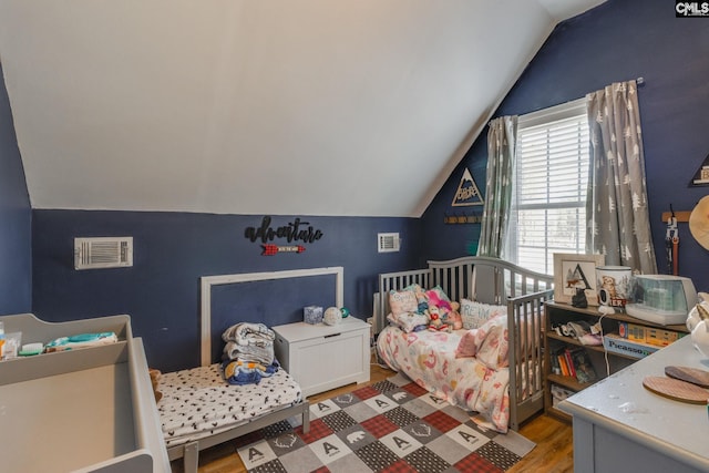 bedroom featuring visible vents, wood finished floors, and vaulted ceiling