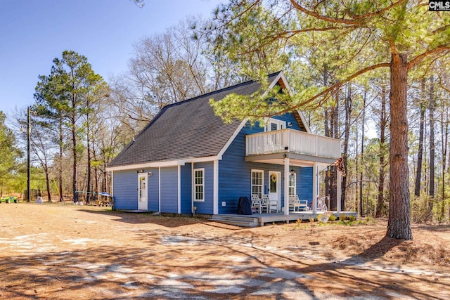 exterior space featuring a balcony, covered porch, and roof with shingles