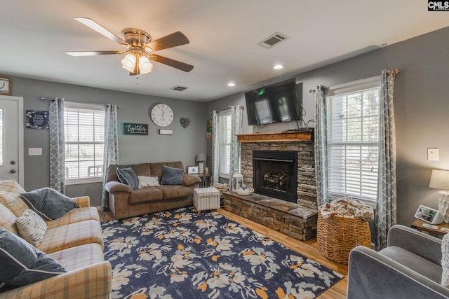 living room featuring visible vents, a fireplace, wood finished floors, plenty of natural light, and a ceiling fan