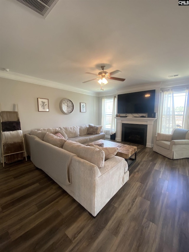 living area with visible vents, dark wood-style floors, a fireplace, crown molding, and ceiling fan