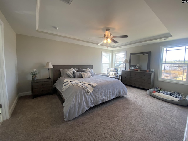 carpeted bedroom with multiple windows, a raised ceiling, visible vents, and a ceiling fan