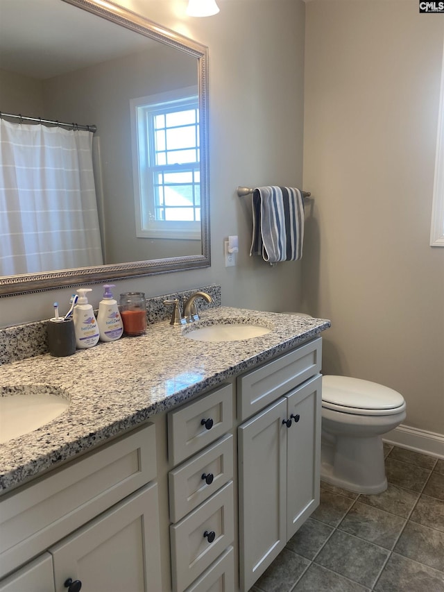 full bath featuring a sink, baseboards, toilet, and double vanity